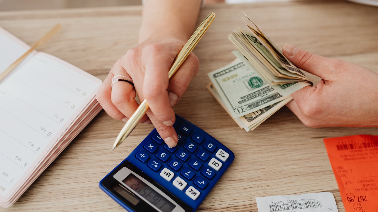 Una persona calcula el ahorro con una calculadora y una hoja de cálculo sobre la mesa.