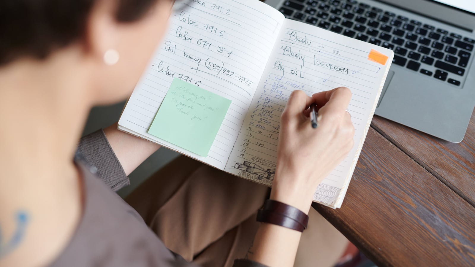 Una persona compara opciones tomando notas junto al portátil, en su escritorio.
