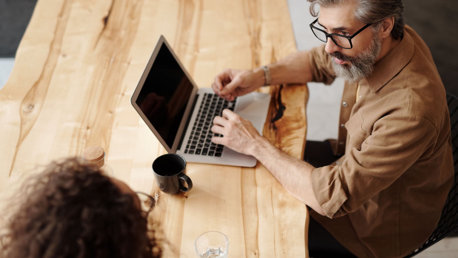 Una persona evalúa y elige una herramienta de software trabajando en el portátil, en una reunión de trabajo.