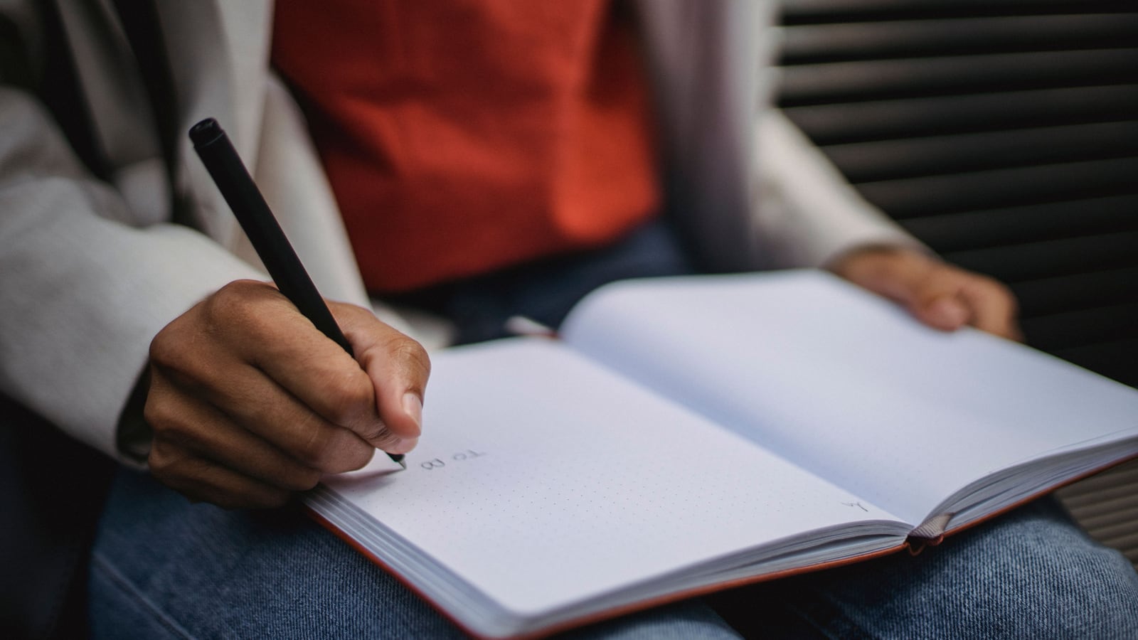 Una persona redacta un procedimiento documentado en un cuaderno, en su mesa.