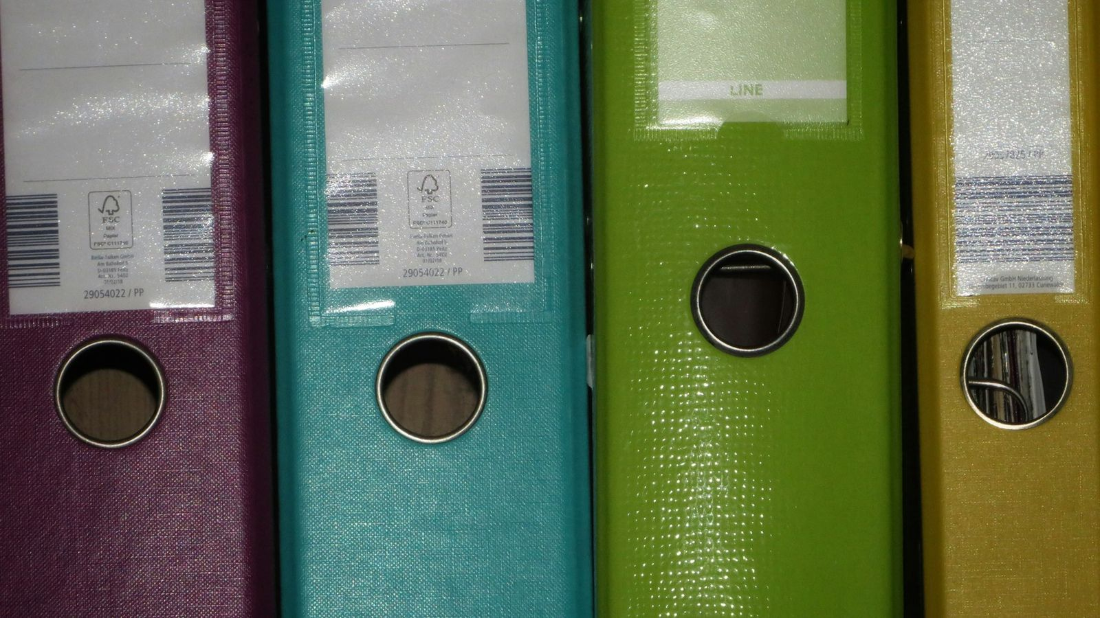 Una fila de carpetas de archivos de colores ordenadas en un estante.